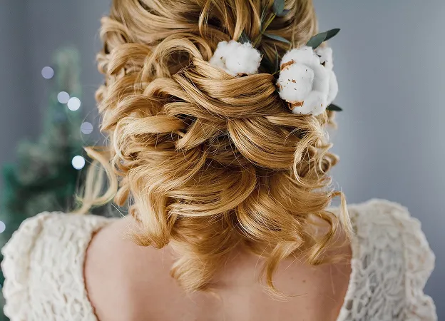 Mariée blonde recevant une coiffure élaborée avec des ornements floraux à Blois dans le Loir-et-Cher 41