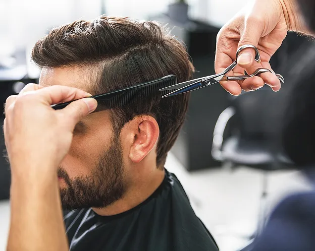 Un barbier coiffe un homme barbu, tenant un peigne et des ciseaux à Blois dans le Loir-et-Cher 41